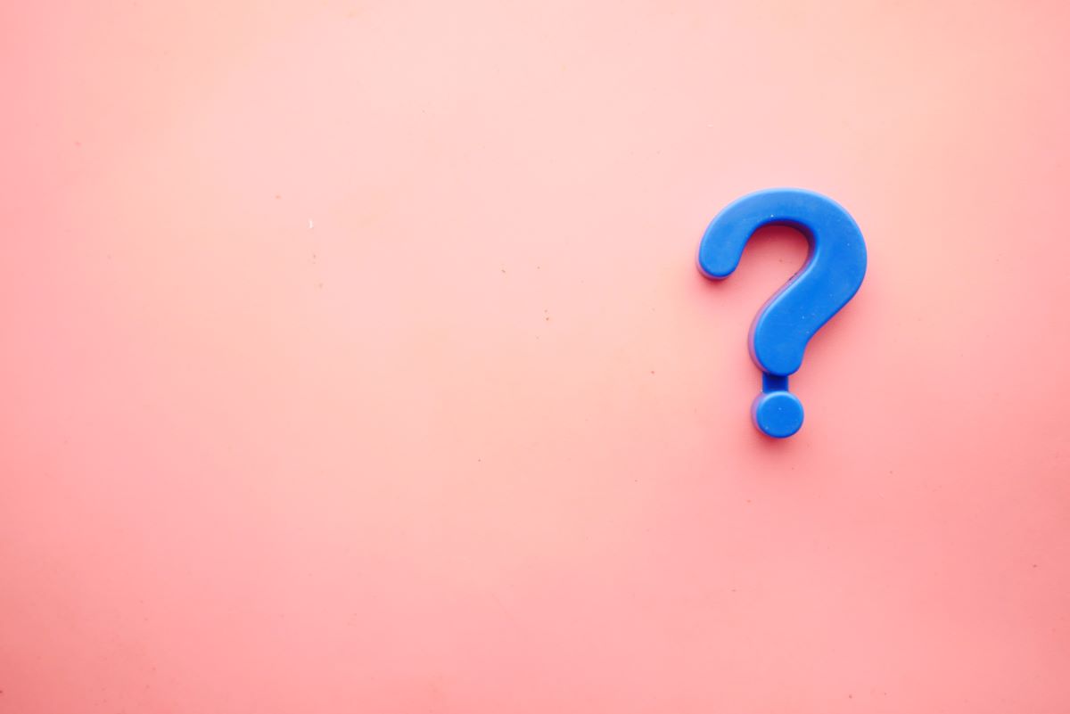 A blue question mark on a pale orange/pink background.