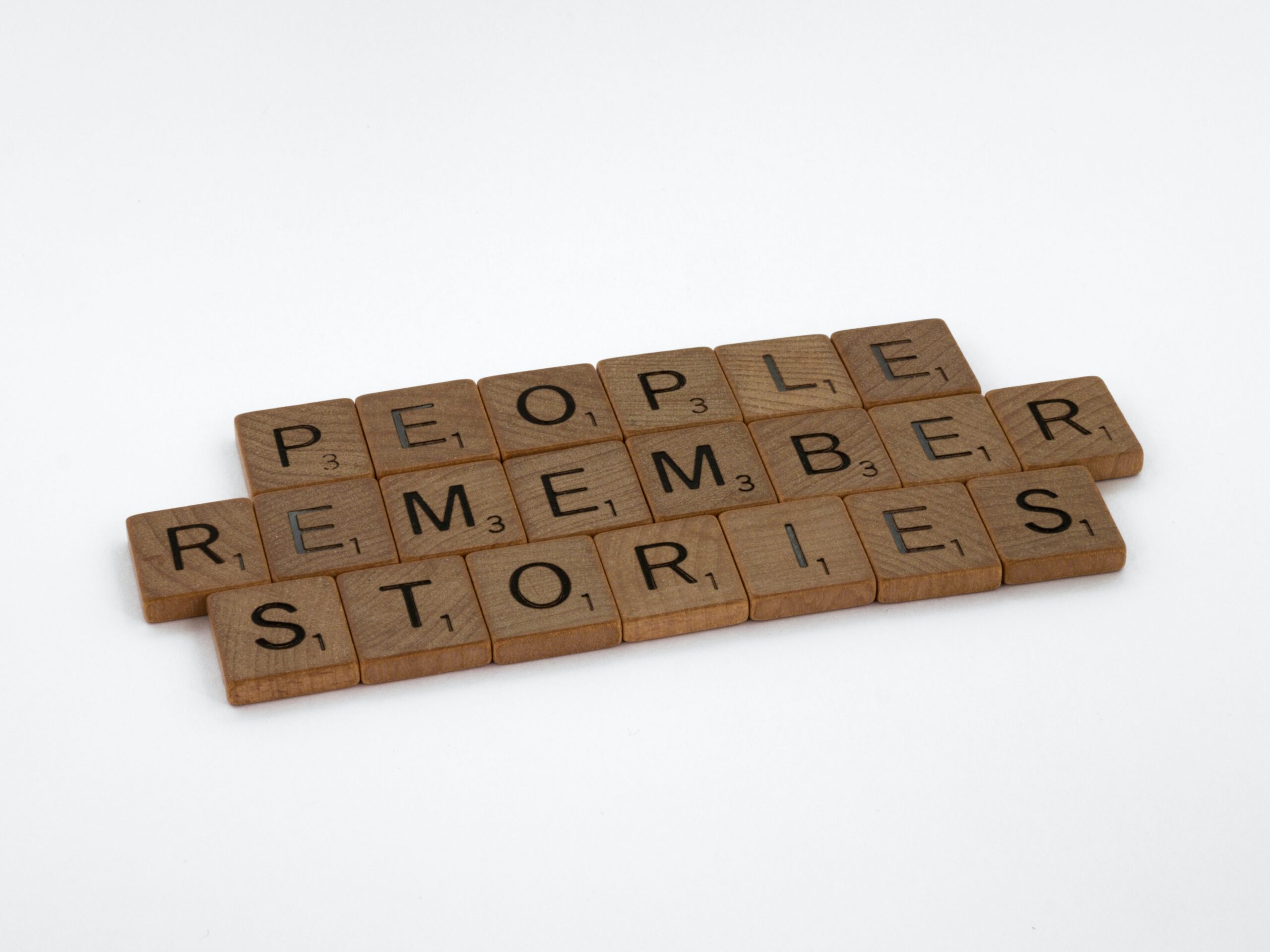 Wooden Scrabble tiles forming three lines that say, 'PEOPLE REMEMBER STORIES'