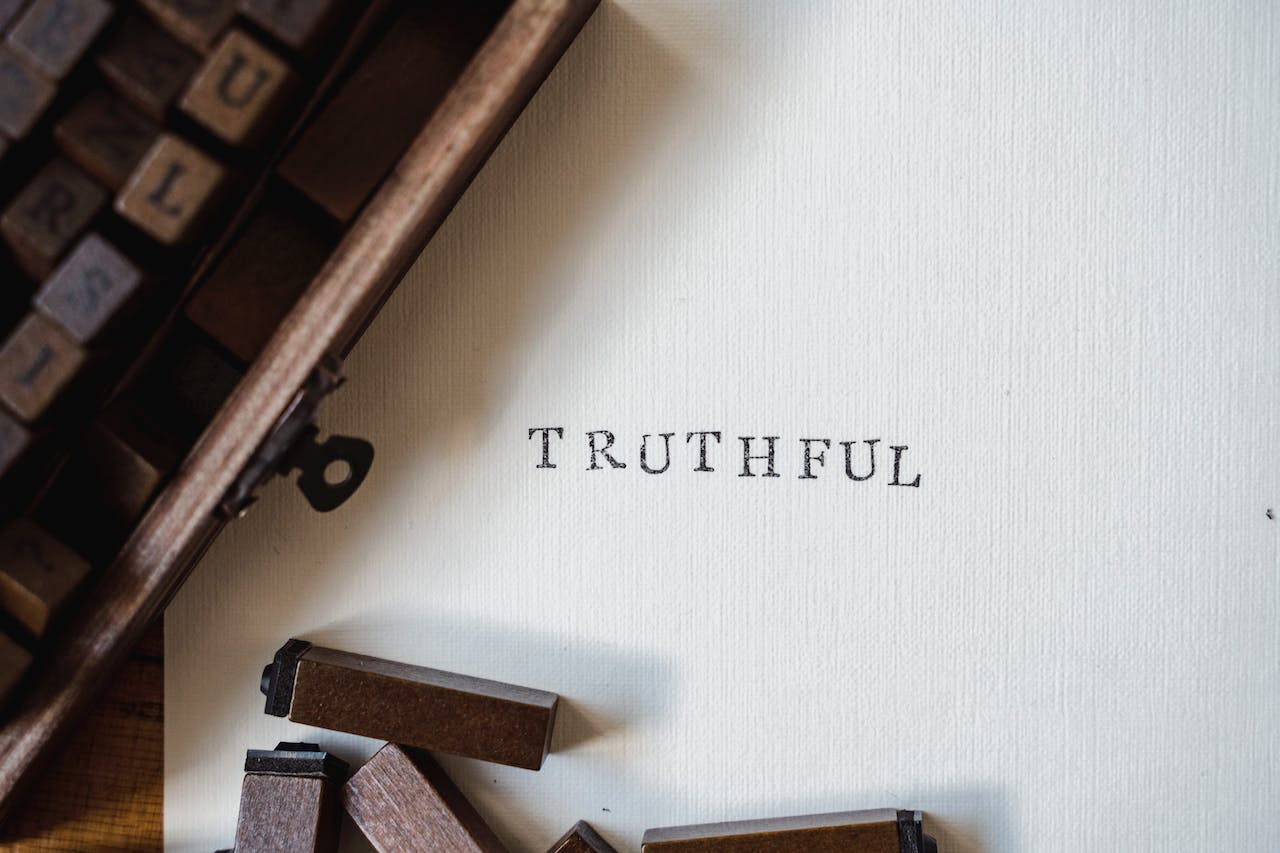 The word 'TRUTHFUL' printed on a white sheet of parchment paper using individual letter stamps.