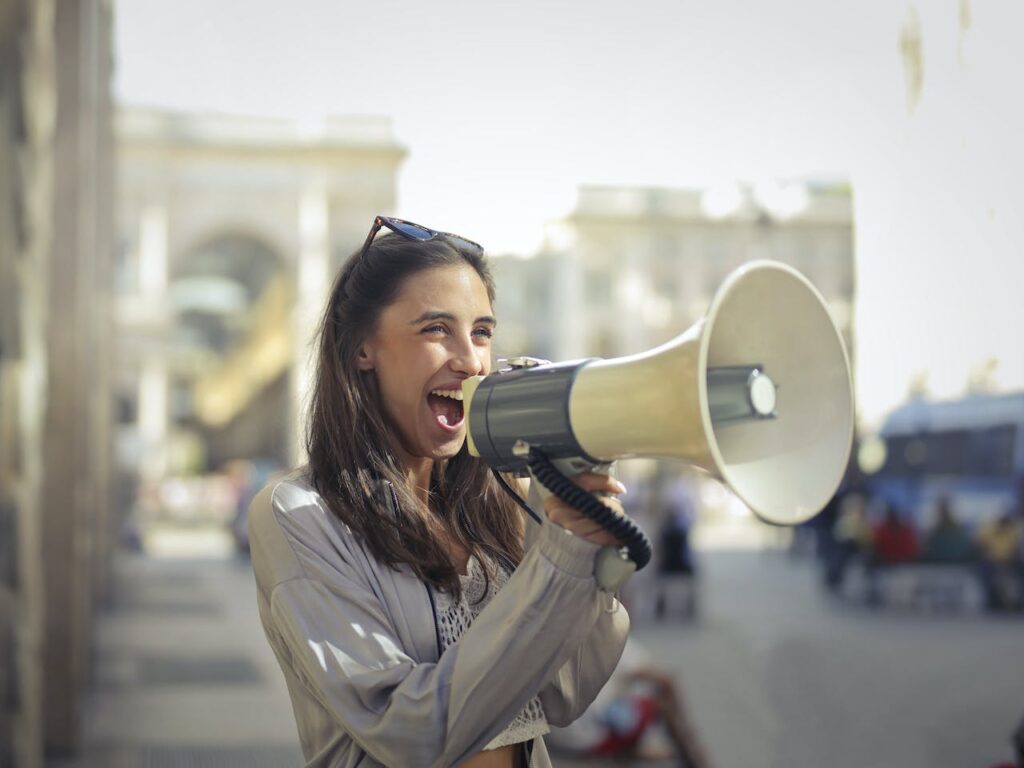 A woman is happily shouting something through a megaphone