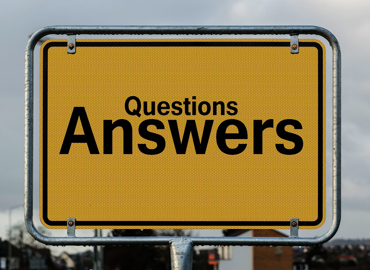 A yellow road sign with two rows of black text showing 'Questions' above 'Answers'