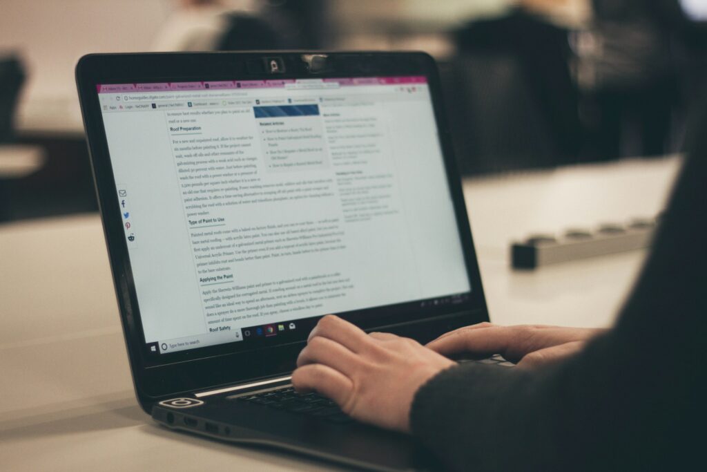 A woman's hands are typing on a laptop keyboard, with the screen showing content that she is working on.