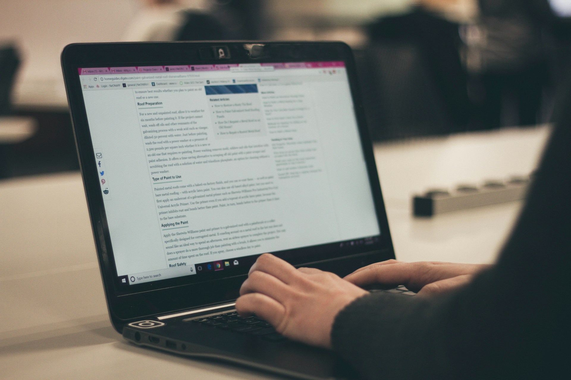 A woman's hands are typing on a laptop keyboard, with the screen showing content that she is working on.